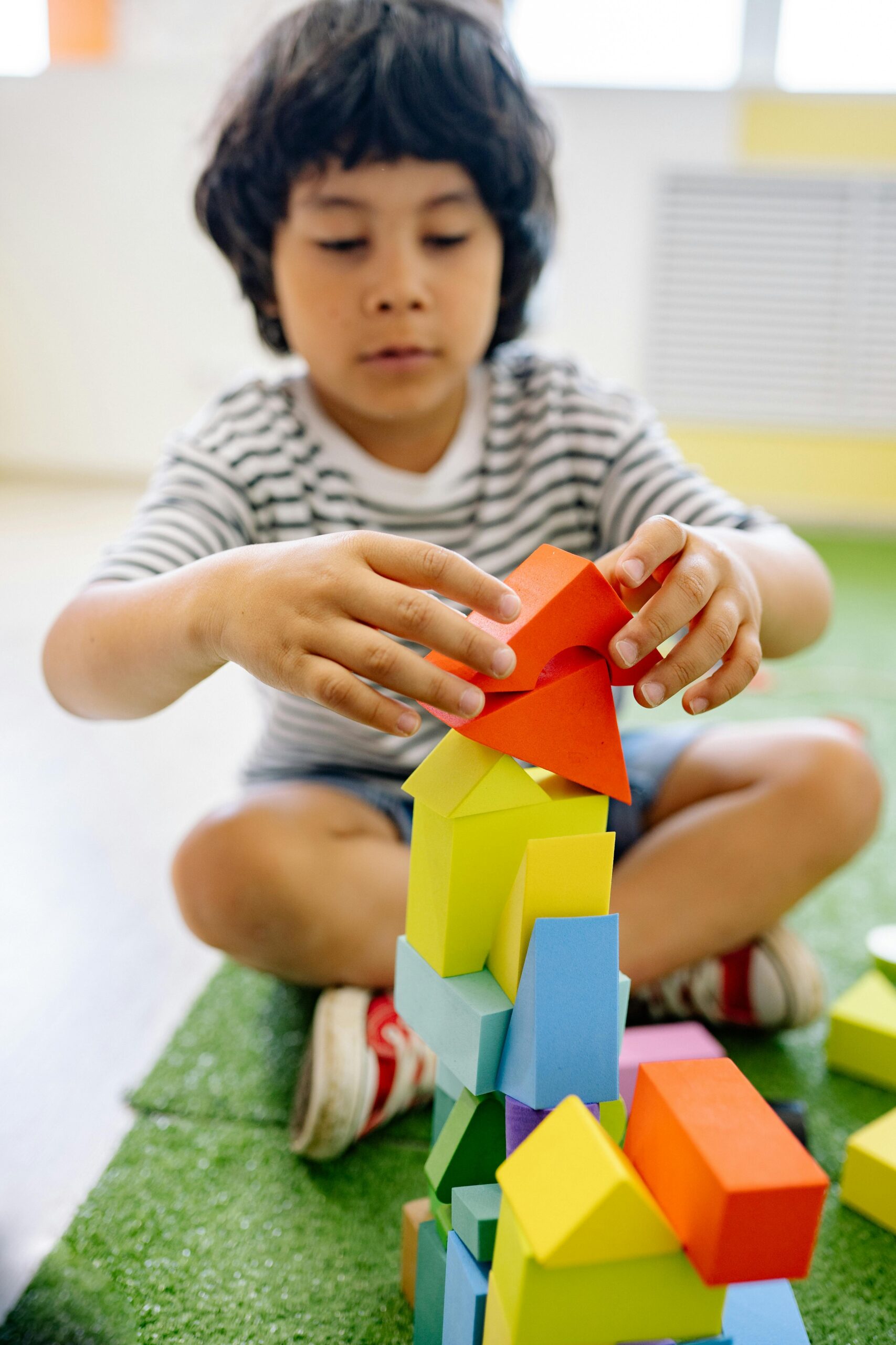 Child plays with stacking blocks as part of play based therapy session
